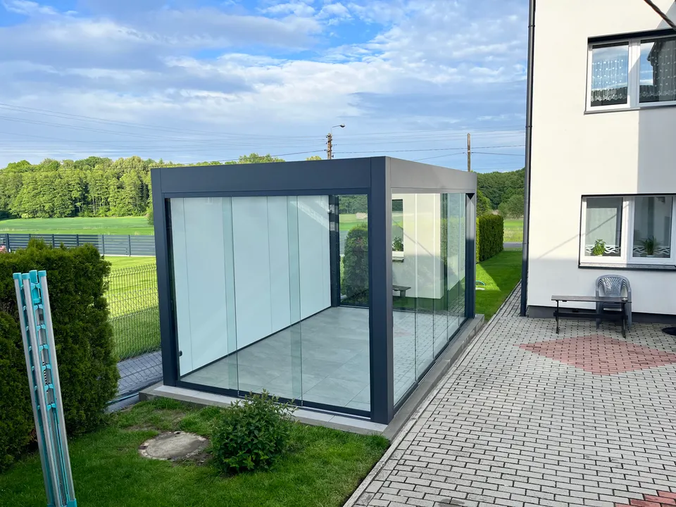 Szklana zabudowa na podłożu z płytkami przy białym domu w Połomi