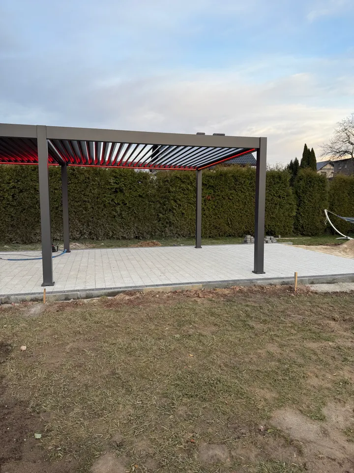 Grafitowa pergola lamelowa w Rydułtowach z otwartym dachem i czerwonym oświetleniem, widok od ogrodu