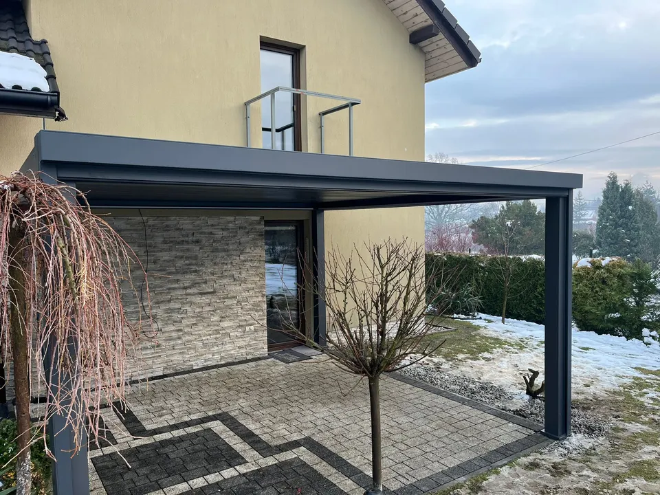 Grafitowa pergola lamelowa przy żółtym domu w Cieszynie, widok od strony ogrodu