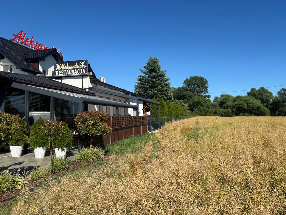 Długie zadaszenie tarasu restauracji w Drogomyślu, widok od strony pola