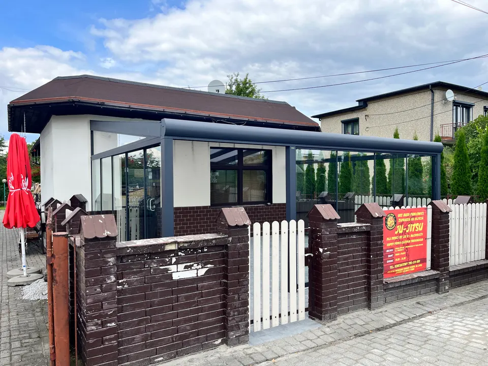 Przeszklony ogródek restauracyjny w Pawłowicach pod grafitowym zadaszeniem, widok z zewnątrz