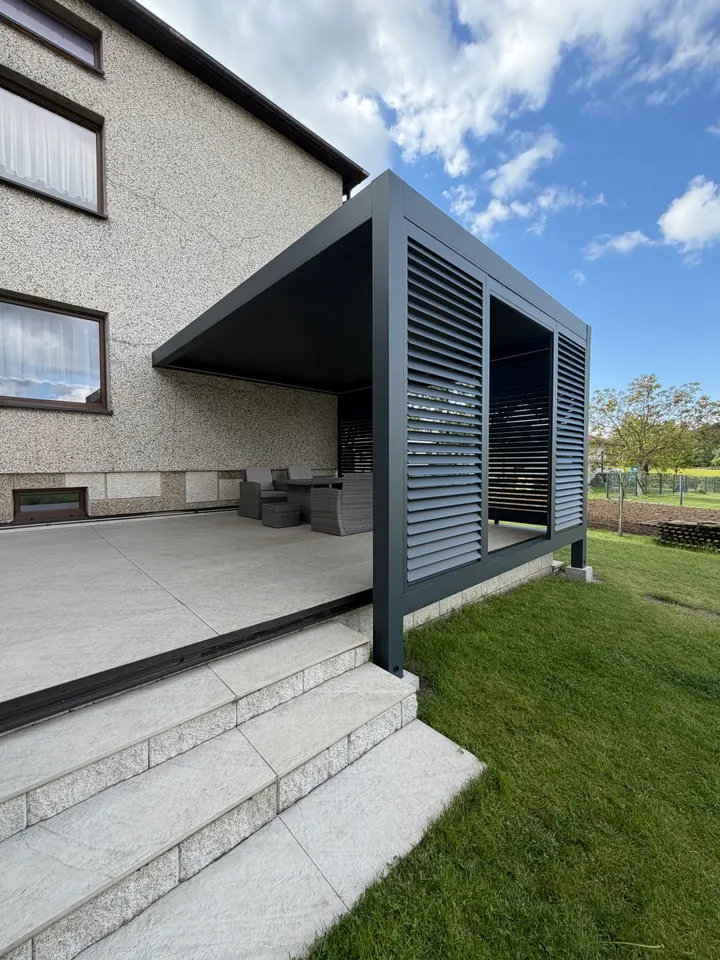 Grafitowa pergola lamelowa przy domu w Świerklanach, z bocznym panelem i otwartym wejściem od schodów