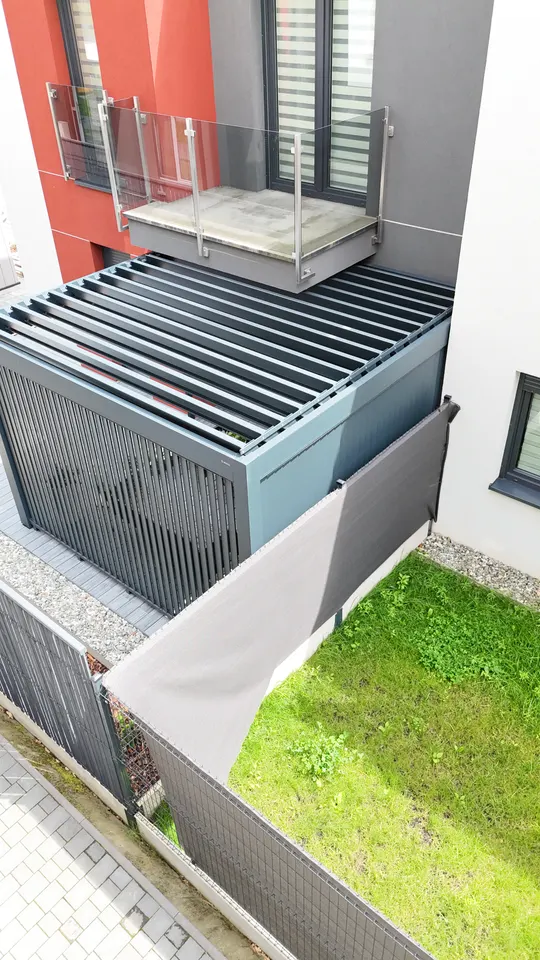 Pergola w Żorach pod balkonem z obróconymi lamelami dachu i pionowym panelem, widok z góry
