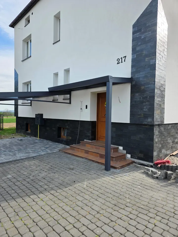 Zadaszenie wejścia połączone z dachem nad tarasem przy domu w Rudołtowicach