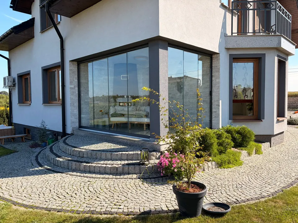 Narożna szklana zabudowa podcienia nad półokrągłymi schodami w Jastrzębiu-Zdroju