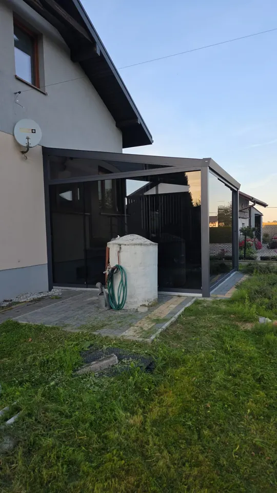 Narożna szklana zabudowa tarasu przy domu w Pawłowicach z grafitowymi profilami