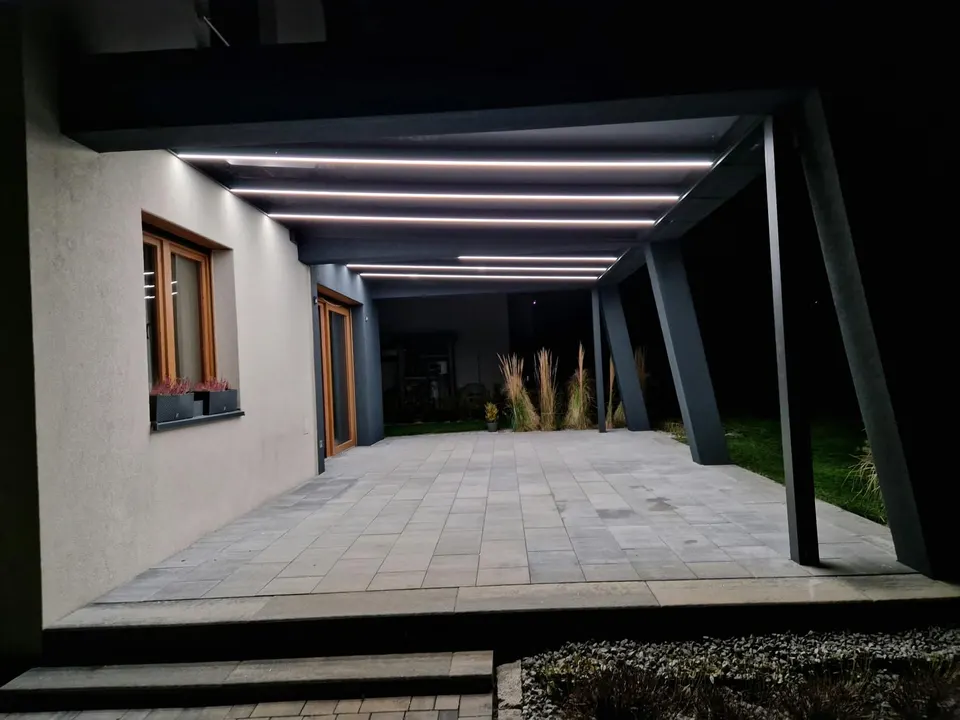 Zadaszony taras w Bielsku-Białej nocą, widok wzdłuż antracytowych słupów i liniowego oświetlenia LED